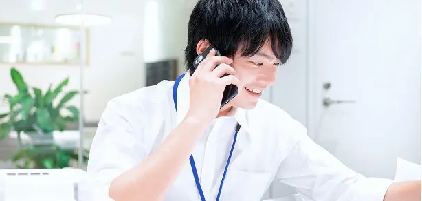 オフィスで笑顔で電話対応する男性社員